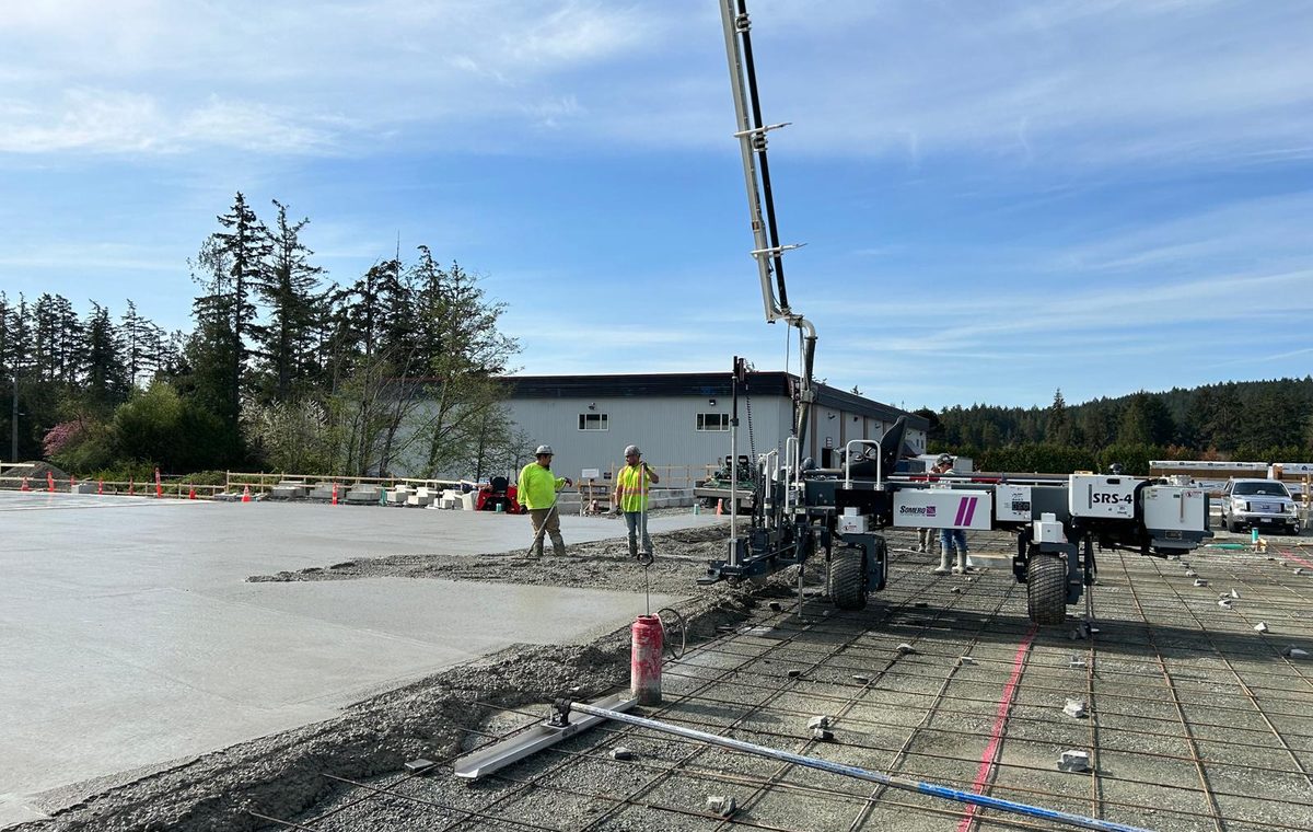 Crew placing a commercial concrete slab on grade with a boom pump