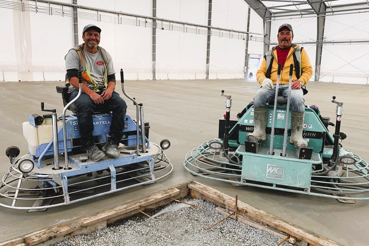 J Andrade crew running ride-on power trowels across an interior slab